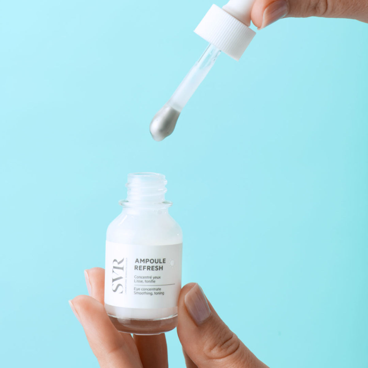 Frasco de vidrio SVR Ampoule Refresh con aplicador de gotero sobre fondo azul claro, ideal para el contorno de ojos.