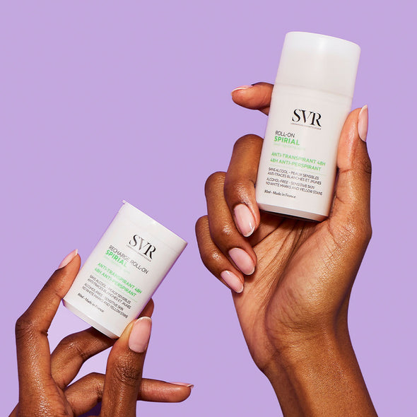 Dos manos de tez morena, mostrando en una mano el producto Spirial recharge Roll-on y en la otyra mano solo el SPIRIAL Roll-on antitranspirante de 50 ml en un fondo morado