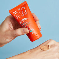 Manos de una mujer aplicando en una de sus manos el Blur Teinte +50spf Sunsecure de SVR con un fondo azul claro