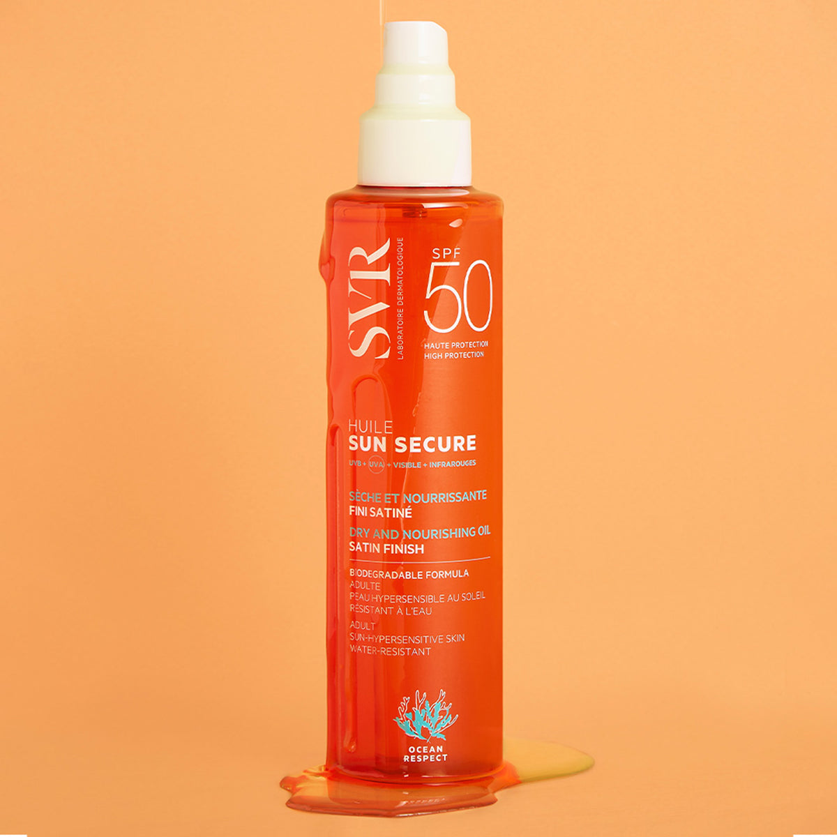 Envase naranja de aceite solar SVR SUN SECURE SPF50 con textura fluida deslizándose sobre un fondo color melocotón.