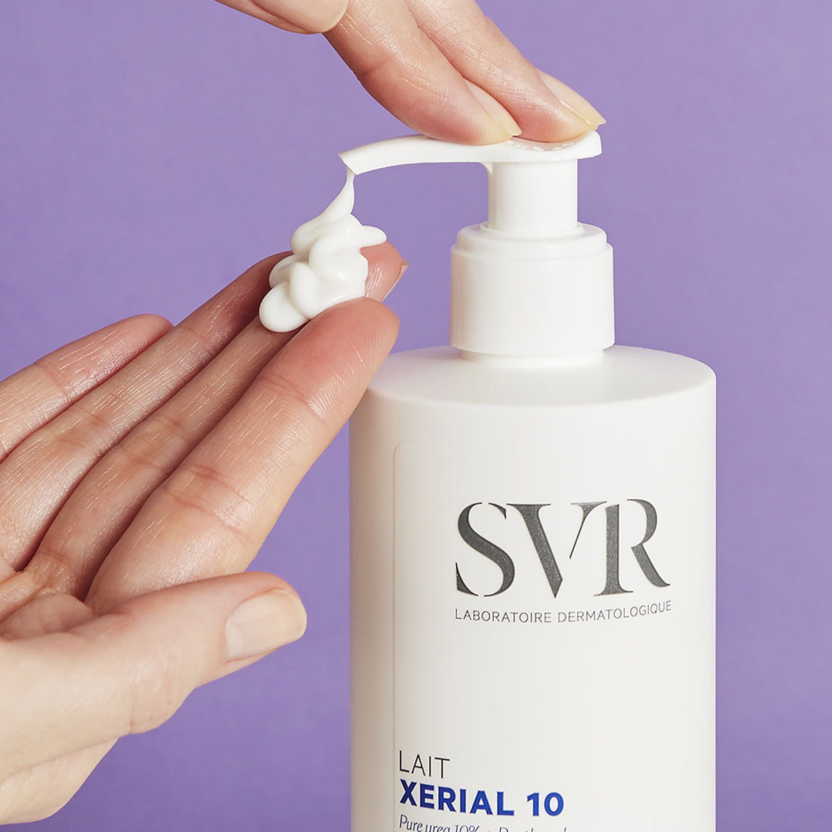 Un par de manos aplicando producto en una de sus manos de forma cremosa del dispensador del Xerial 10 Lait de SVR, con fondomorado