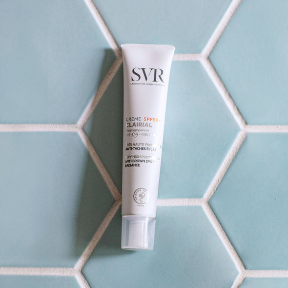Envase de la Creme SPF+50 Clairial de SVR sobre un azulejo color azul