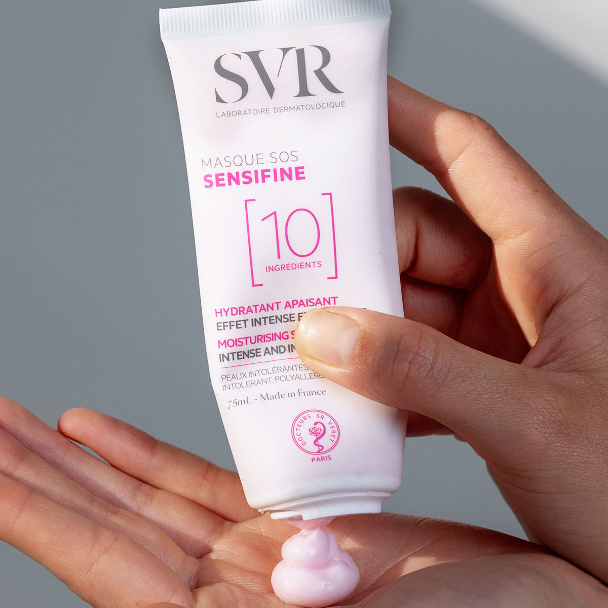 Las manos de una mujer aplicandose producto de la Sensifine Masque SOS de SVR, en un fondo gris