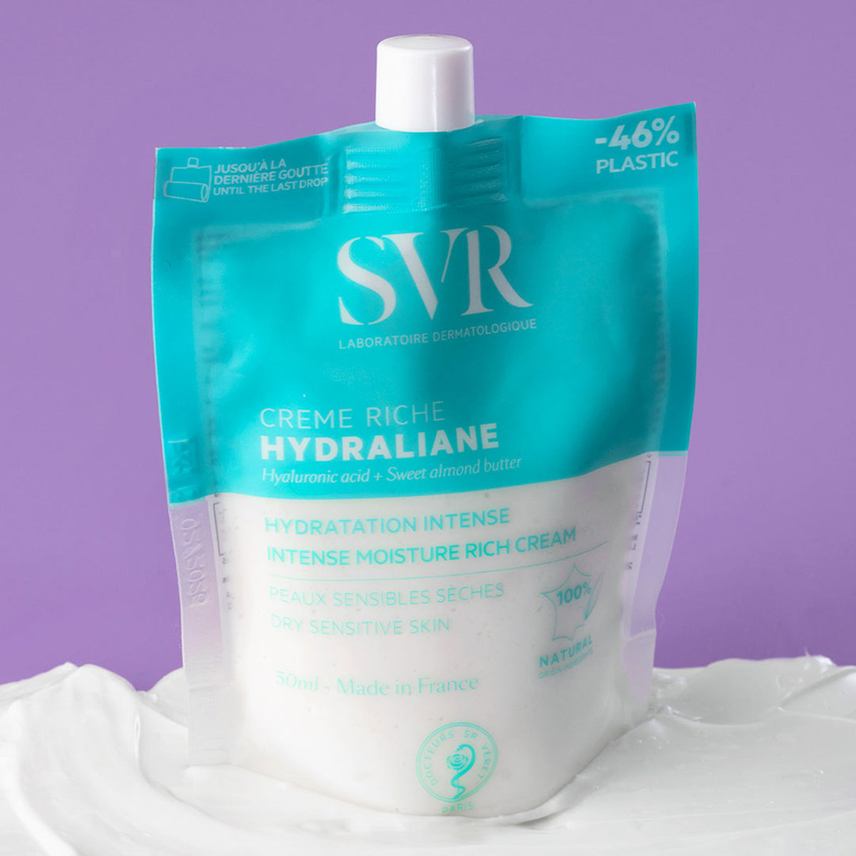 Envase flexible de 50 ml de crema hidratante SVR Hydraliane Crème Riche sobre una textura cremosa blanca.
