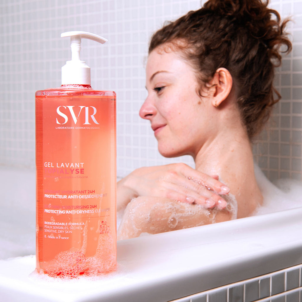 Brown-haired woman in a bath next to SVR Topialyse Gel Lavant cleanser perfect for dry and atopic skins