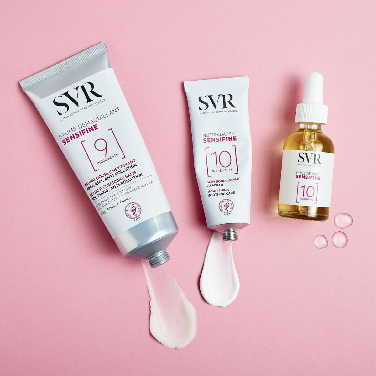 Tubos de SVR Sensifine y aceite facial sobre fondo rosa, mostrando texturas cremosas y gotas de producto hidratante.